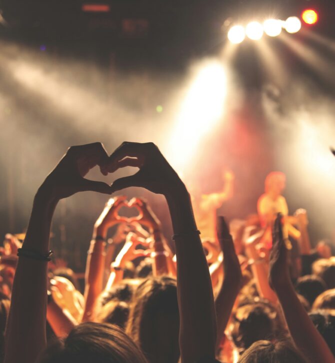 Cheering at a gig, peoples hands in the air and making a heart symbol