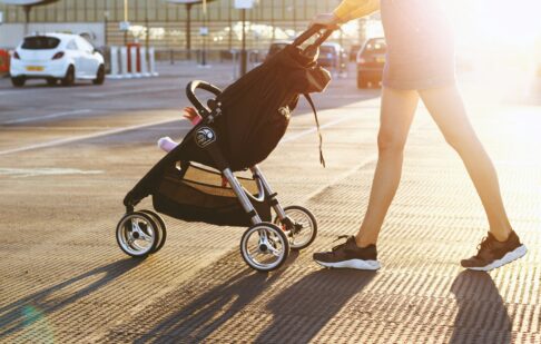 Woman pushing a pram in a car park looking for parent and child parking